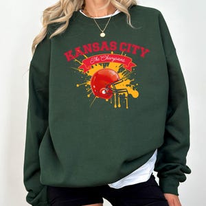 a woman wearing a green sweatshirt with a football helmet on it