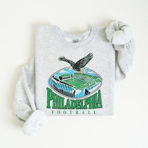 A gray sweatshirt with a graphic of Philadelphia Eagles football stadium and an eagle in flight.
