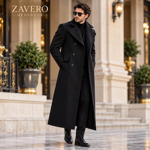 Puede incluir: Un abrigo largo negro de doble botonadura con solapas anchas y tres botones visibles, usado sobre un cuello alto negro y pantalones negros. El texto ZAVERO MENSWEAR es visible en la esquina superior izquierda de la imagen.