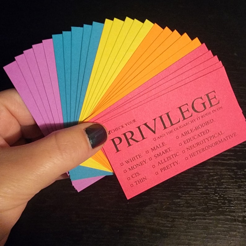 Puede incluir: Un juego de cartas de colores con la palabra "Privilegio" impresa en negro en una tarjeta roja. Las cartas enumeran varias ventajas sociales, incluyendo "Blanco", "Masculino", "Dinero", "Inteligente", "Con capacidad f&iacute;sica", "Educado", "Cis", "Al&iacute;stico", "Neurot&iacute;pico", "Bonito", "Delgado", y "Heteronormativo".