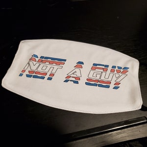 May include: White face mask with the text "NOT A GUY" in blue, red and white stripes.