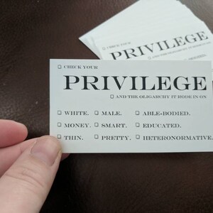 Puede incluir: Una tarjeta blanca con el texto "Check Your Privilege" y una lista de privilegios, que incluyen "Blanco", "Masculino", "Con capacidades", "Dinero", "Inteligente", "Educado", "Delgado", "Bonito" y "Heteronormativo".