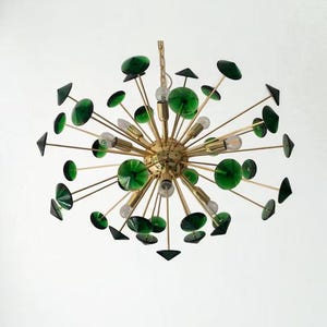 May include: A sputnik-style chandelier featuring a central brass sphere with numerous radiating metal arms. Each arm terminates in a small, circular, translucent emerald green glass disc. Several clear light bulbs are interspersed throughout.