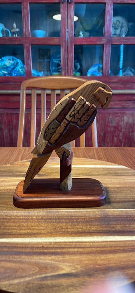 A hand-carved wooden parrot that doubles as a secret-compartment puzzle box — the kind of object people pick up, fidget with, and can't put down.
