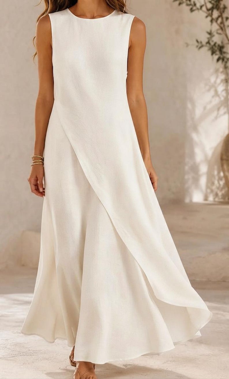 May include: A sleeveless, floor-length dress in a solid off-white color. The garment features a high, round neckline and a distinctive wrap-style front panel that creates an overlapping diagonal line, resulting in a flowing, flared skirt silhouette.
