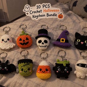May include: A set of 10 crochet Halloween keychains featuring a ghost, pumpkin, skull with top hat, witch hat, black cat, bat, Frankenstein monster, candy corn, cauldron, and mummy. The sign above reads 10 PCS Crochet Halloween Keychain Bundle.