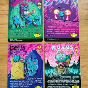 May include: Four rectangular trading cards featuring colorful, stylized goblin illustrations. The cards are titled Goblin Matron, Goblin Lackey, Goblin Recruiter, and Muxus, Goblin Grandee, each displaying specific game text, creature types, and power/toughness stats.