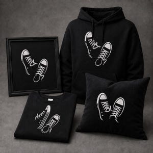 Może przedstawiać: Czarna bluza z kapturem, czarny t-shirt z okrągłym dekoltem, czarna kwadratowa poduszka i czarny oprawiony wydruk, każdy z białą grafiką przedstawiającą parę wysokich trampek ze sznurowadłami i gumowymi noskami.