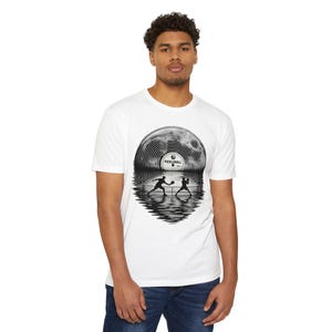 May include: A white short-sleeve t-shirt featuring a black and white graphic of a vinyl record that transitions into a pickleball court scene. The centre label of the record displays the text PICKLEBALL, with silhouettes of two players in action.