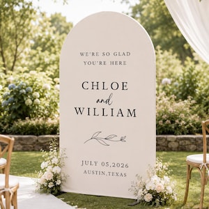 Może przedstawiać: Wysoki, łukowaty, kremowobiały znak powitalny na ślub z czarnym napisem: WE'RE SO GLAD YOU'RE HERE, CHLOE and WILLIAM, JULY 05, 2026, AUSTIN, TEXAS, oraz małym rysunkiem liniowym gałązki z liśćmi umieszczonym między imionami a datą.