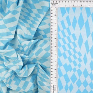 May include: A light blue and white diamond patterned fabric featuring a repeating geometric lozenge design. A ruler is placed vertically along the edge, showing measurements in both inches up to 8 inches and centimeters up to 21 centimeters.