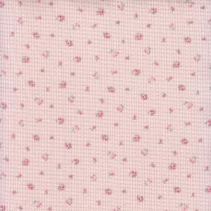 May include: A light pink waffle knit fabric featuring a repeating pattern of tiny, scattered rosebuds in shades of pink and green. The texture of the fabric is clearly visible, showing a grid-like pattern across the entire surface of the material.