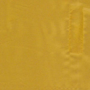 May include: A solid mustard yellow fabric with a smooth, matte texture. The material features a single vertical rectangular stitched seam detail on the right side, creating a subtle raised edge against the flat surface of the textile.