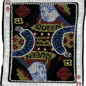 May include: A rectangular embroidered patch shaped like a playing card, featuring a Queen of Diamonds design. The black background is accented with red and yellow geometric patterns, blue curved shapes, and the text QUEEN OF DIAMONDS.