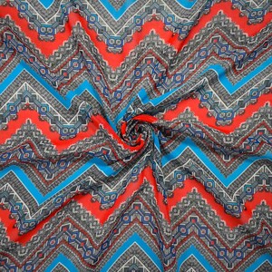 May include: A lightweight fabric featuring a vibrant chevron pattern in bright red, electric blue, and black and white geometric details. The material is gathered in the center, creating soft folds that highlight the repeating zigzag design.