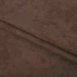 May include: A solid dark brown fabric with a soft, matte, and slightly textured surface. The material is folded, creating a diagonal crease that runs across the frame, highlighting the consistent color and the fine, suede-like nap of the textile.
