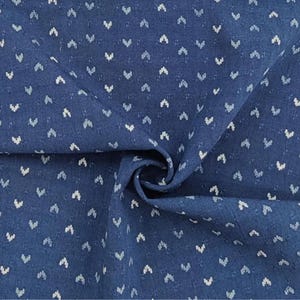May include: A deep blue fabric featuring a repeating pattern of small, light-colored chevron or V-shaped marks arranged in a grid. The textile has a visible woven texture with subtle horizontal and vertical lines throughout the material surface.