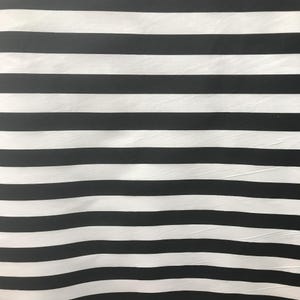 May include: A fabric textile featuring a repeating pattern of horizontal stripes in alternating black and white colors. The material has a smooth, slightly textured surface with visible folds and creases running across the width of the fabric.