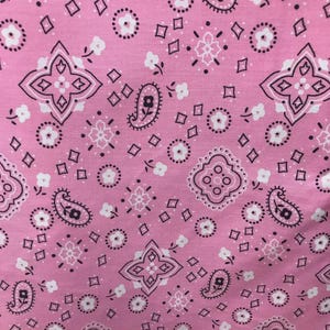 May include: A fabric featuring a repeating bandana pattern in shades of pink, white, and black. The design consists of intricate paisley motifs, small floral shapes, and geometric diamond outlines arranged in a symmetrical, dense layout across the surface.