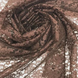 May include: A dusty rose lace fabric featuring a delicate, repeating floral pattern. The material is semi-sheer with an intricate, open-work design that creates a textured, layered appearance as it is gathered and draped in soft, flowing folds.