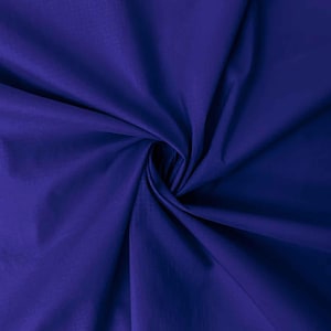 May include: A solid deep royal blue fabric featuring a smooth, matte texture. The material is gathered in the center, creating soft, radiating folds and shadows that highlight the consistent, vibrant blue color across the entire surface area.