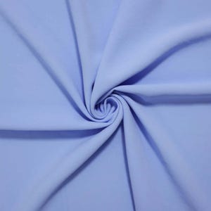 May include: A solid light blue fabric featuring a smooth, matte texture. The material is gathered in the center, creating soft, radiating folds and drapes that extend outward toward the edges, showcasing the consistent color and textile surface.