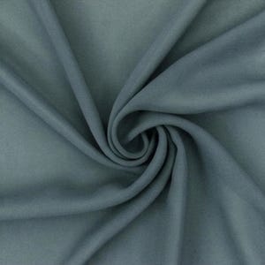 May include: A solid slate blue fabric with a smooth, matte texture. The material is gathered in a central spiral, creating deep, flowing folds and soft shadows that highlight the consistent color and uniform surface of the textile throughout.