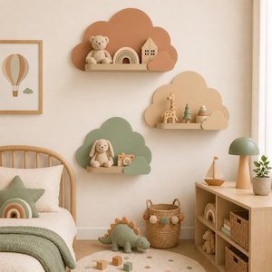 May include: Three cloud-shaped wall shelves in terracotta, beige, and sage green. The shelves hold small toys including a teddy bear, a wooden rainbow, a house, a giraffe, a tree, a stacking toy, a plush bunny, and a wooden toy camera.