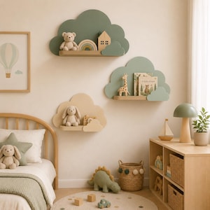 Puede incluir: Tres estantes de pared con forma de nube en verde salvia y beige, montados en la pared. El estante superior sostiene un oso de peluche, un arcoíris de madera y una casa. El estante central sostiene una figura de jirafa y libros.