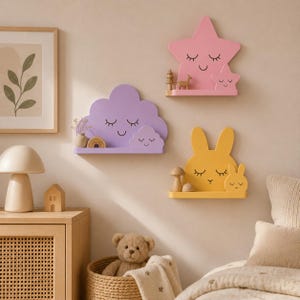 May include: Three wall-mounted shelves shaped like a pink star, a purple cloud, and a yellow rabbit. Each shelf features a smaller matching icon with a sleepy face, including closed eyes and a smile, providing a flat surface for small decorative items.