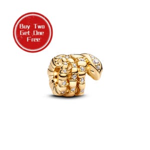 Könnte beinhalten: Ein goldfarbener Schlangen-Charm-Bead mit gewundenem Körperdesign und eingelassenen klaren Steinen auf der Oberfläche. Ein rotes kreisförmiges Abzeichen in der oberen linken Ecke zeigt den weißen Text Buy Two Get One Free.