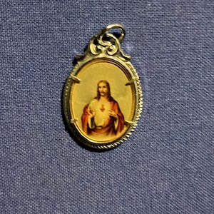 Pretty vintage medal of Jesus. Jesus is in full color as an illustration. Silvertone light weight design.