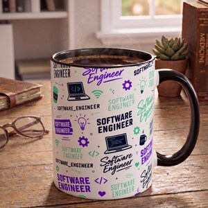May include: A white ceramic mug with a black interior and handle, featuring a repeating pattern of the text "Software Engineer" in purple, black, and teal, interspersed with icons of laptops, light bulbs, gears, and code brackets.