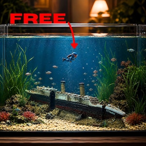 Könnte beinhalten: Ein klares Glasaquarium mit einem Miniatur-Titanic-Wrackmodell auf sandigem Boden, grünen Wasserpflanzen und kleinen Fischen. Eine kleine blaue Taucherfigur schwebt über dem Wrack, darüber steht der rote Schriftzug FREE.