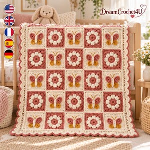 May include: A rectangular crochet blanket featuring a repeating grid pattern of alternating squares. One set of squares displays a white flower with a dusty rose centre, while the other set features a butterfly motif in dusty rose and mustard yellow.