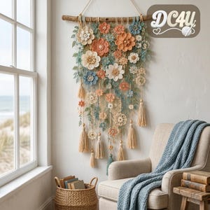 Può includere: Una decorazione da parete con una collezione di fiori all'uncinetto nei toni in tonalità pesca, crema e blu, sospesa a un ramo di legno. L'oggetto include delicate foglie verdi, intricati motivi circolari in pizzo e nappe beige pendenti.