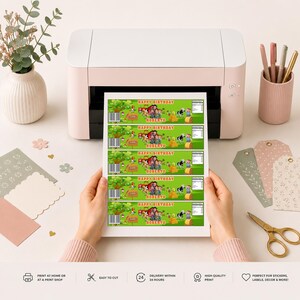 May include: A white printer outputting a sheet of five identical rectangular labels featuring a green farm scene with a red tractor, a cow, hay bales, and the text Happy Birthday Roberto. The labels include a barcode and nutrition facts.