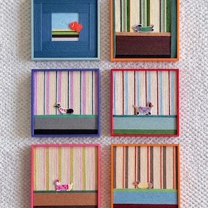 May include: Six square wall art pieces featuring colorful frames and thread-wrapped backgrounds. Each piece displays a small animal figure, including a goldfish and five dogs in various sweaters, set against striped or solid-colored thread patterns.