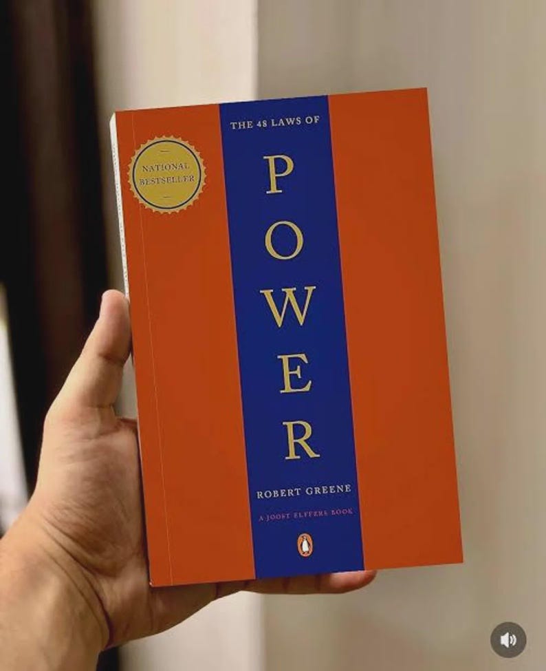May include: A paperback book titled The 48 Laws of Power by Robert Greene and Joost Elffers. The cover features a vertical blue stripe on an orange background with gold text. A gold circular seal on the top left reads National Bestseller.