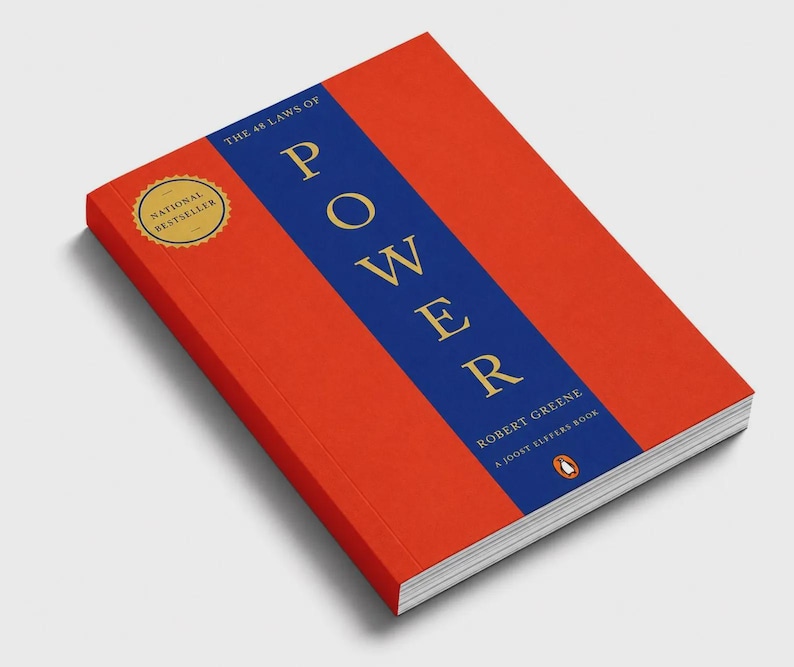May include: A book titled The 48 Laws of Power by Robert Greene. The cover is bright orange with a vertical blue stripe down the center featuring the title in gold lettering. A gold circular seal on the top left reads National Bestseller.