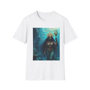 May include: A white t-shirt featuring a graphic print of a figure with long dark hair, wearing a golden crown and holding a trident underwater. The text Born of the Ocean, Forged by the Future, Crowned in Power is printed above the figure in the graphic.