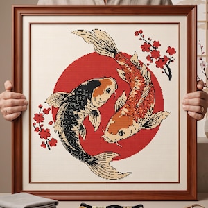 Peut inclure: Une broderie au point de croix encadrée représentant deux poissons koï nageant en cercle sur un fond de cercle rouge uni. Les poissons sont rendus en noir, blanc et orange, agrémentés de petites branches de fleurs de cerisier rouges.