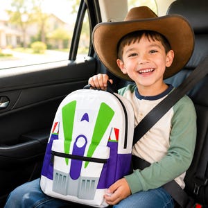 May include: A white, green, and purple backpack featuring a graphic design inspired by a space ranger suit, including a front zippered pocket, black trim, and a top handle, designed for carrying personal items and school supplies.