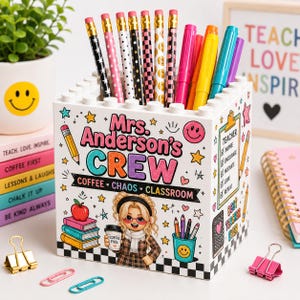 May include: A white square pencil holder with a building block top edge, featuring the text "Mrs. Anderson's CREW" and "COFFEE CHAOS CLASSROOM". The design includes a cartoon character, a checklist, and various school-themed icons in bright colors.