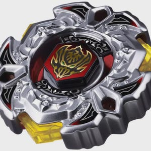 Puede incluir: Un juguete de peonza circular con un anillo exterior de metal plateado con detalles en negro y rojo. El centro muestra un perno hexagonal rojo con un dise&ntilde;o gr&aacute;fico dorado. Debajo del marco plateado se ven componentes de pl&aacute;stico amarillo transl&uacute;cido.
