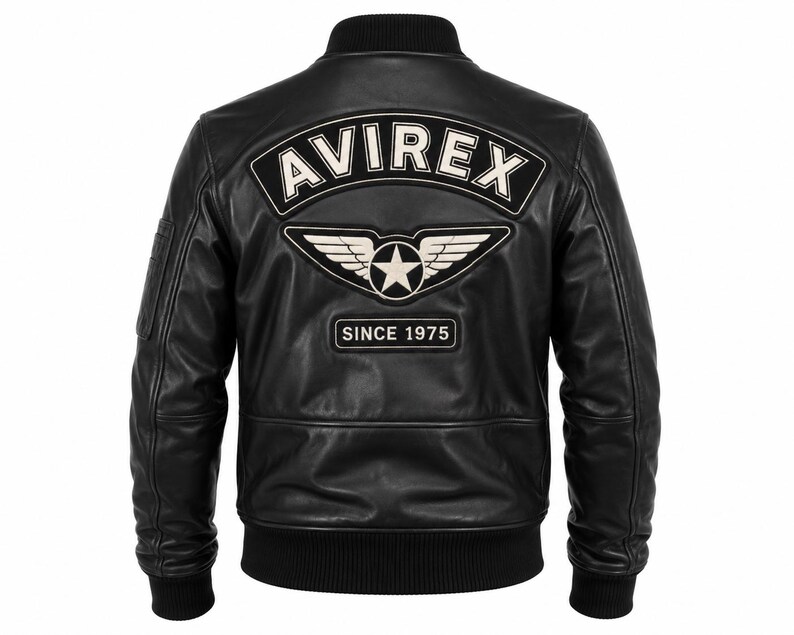 May include: A black leather bomber jacket featuring a ribbed collar, cuffs, and hem. The back displays a large embroidered patch with the text AVIREX in white, a winged star emblem, and a rectangular patch below reading SINCE 1975 in white.