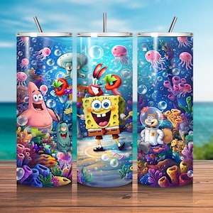Pode incluir: Um copo cilíndrico de metal com uma cena subaquática vibrante apresentando Bob Esponja, Patrick Estrela, Lula Molusco, Sr. Siriguejo, Plankton e Sandy Bochechas. O design inclui corais coloridos, bolhas flutuantes e águas-vivas rosas.