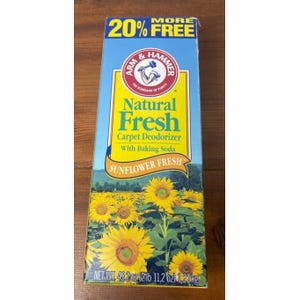 Könnte beinhalten: Eine rechteckige Packung Arm & Hammer Natural Fresh Teppich-Deodorizer mit Natron im Duft Sunflower Fresh. Die blau-gelbe Verpackung zeigt ein Sonnenblumenfeld und trägt die Aufschrift 20% More Free mit einem Nettogewicht von 1,22 kg.