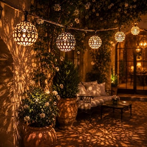 Può includere: Una serie di lanterne sferiche in metallo con intricati motivi ritagliati, che emettono una calda luce dorata. Le luci sono sospese in fila, proiettando ombre dettagliate e simili a pizzi sulle pareti in pietra circostanti.
