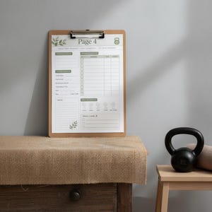 Puede incluir: Un portapapeles de madera con una hoja de seguimiento de fitness blanca etiquetada como Page 4, con detalles de hojas verdes y un icono de pesa rusa. El documento incluye secciones para detalles de entrenamiento, resultados y notas diarias.